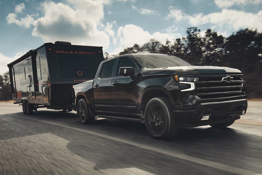 A black 2026 Chevrolet Silverado 1500 truck towing a black trailer