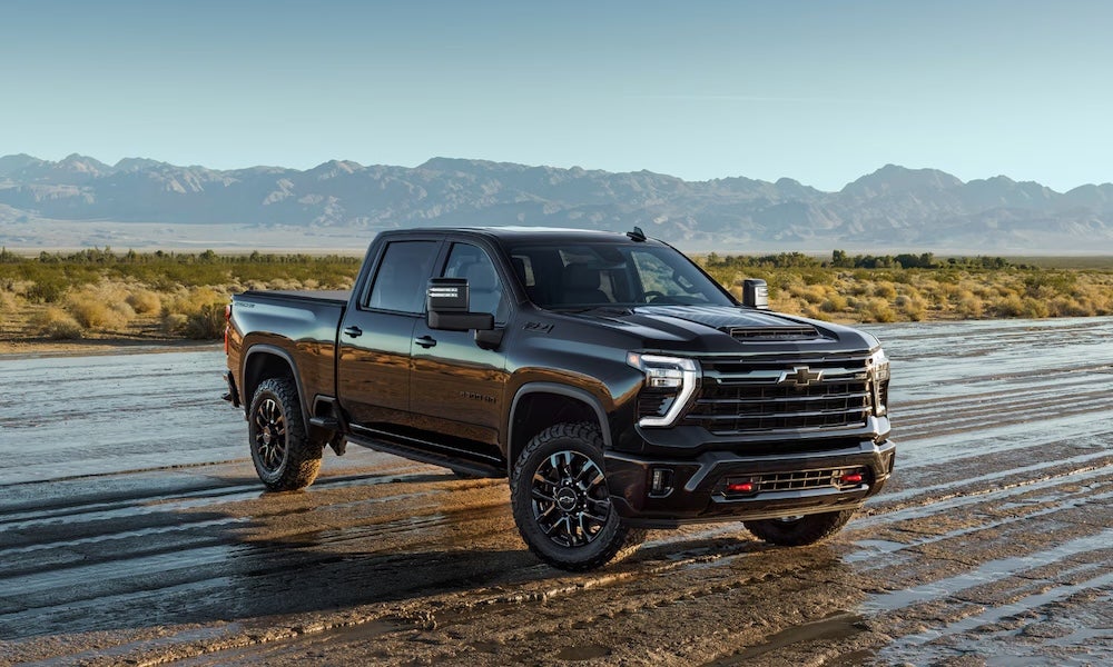 A black 2026 Chevrolet Silverado 2500 HD pickup truck parked in a dirt field