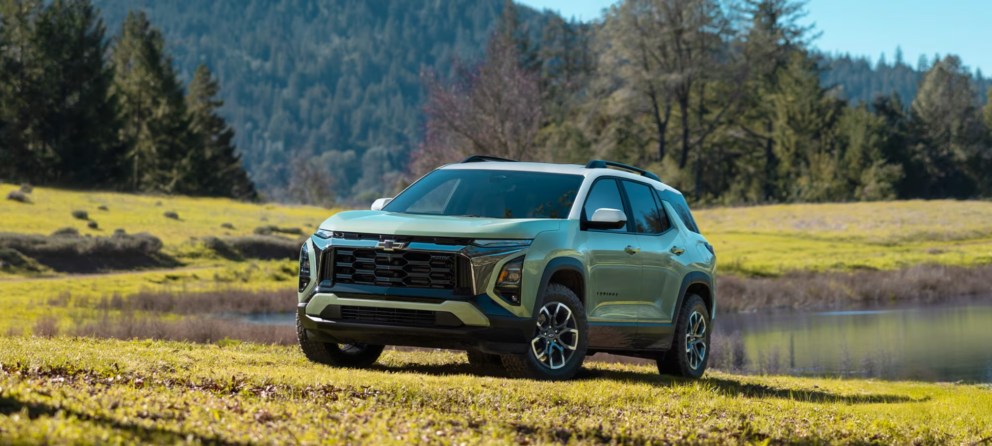 A light green 2026 Chevrolet Equinox parked beside a mountain lake