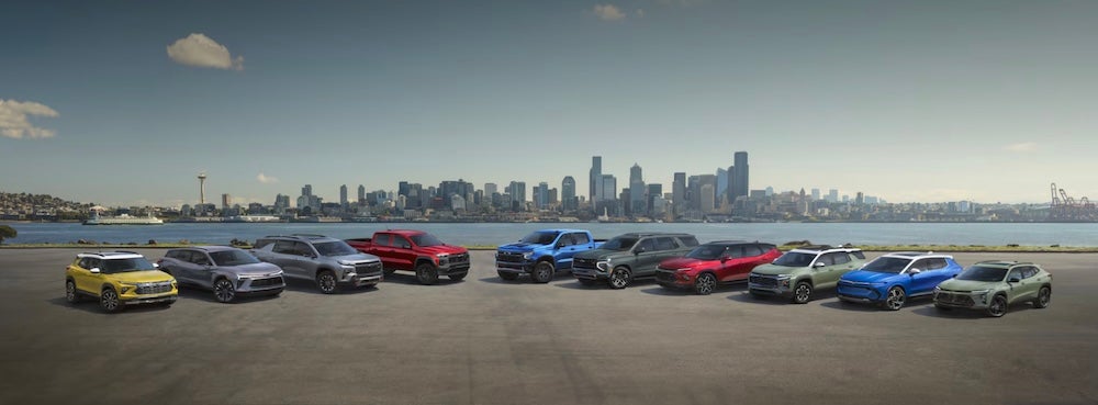 A selection of Chevrolet vehicles parked across the river from a city